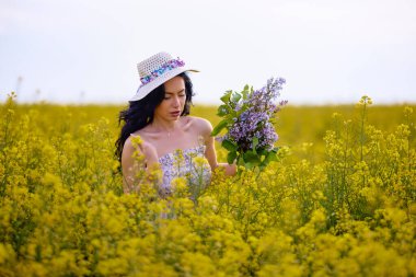 Baharda kolza tohumu tarlasında esmer bir kadının portresi.