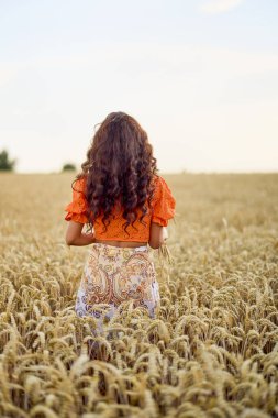 Buğday tarlasında poz veren uzun saçlı güzel bir kadın. kavramsal moda görüntüsü.