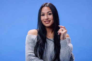 Stüdyoda mavi arka planda poz veren güzel esmerin portresi.