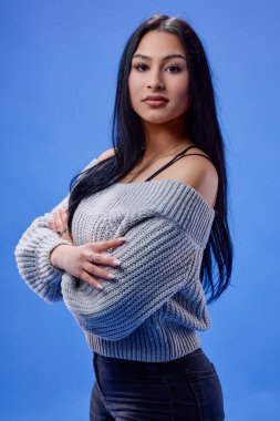 Stüdyoda mavi arka planda poz veren güzel esmerin portresi.