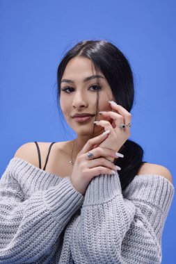 Stüdyoda mavi arka planda poz veren güzel esmerin portresi.