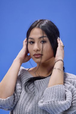 Stüdyoda mavi arka planda poz veren güzel esmerin portresi.