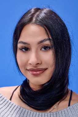 Stüdyoda mavi arka planda poz veren güzel esmerin portresi.