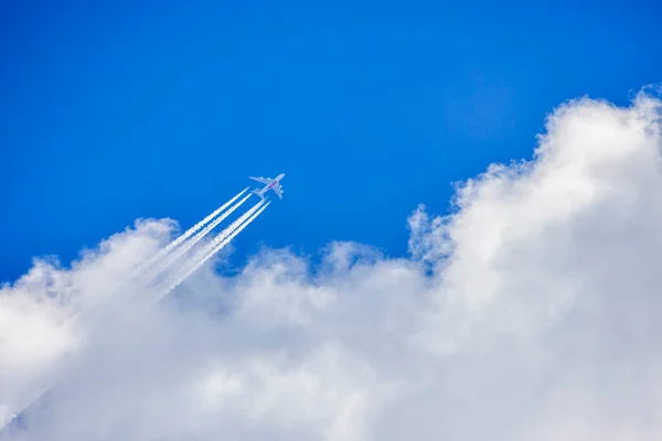 Samolot Przelatujący Przez Błękitne Zachmurzone Niebo Zostawiający Sobą Białe Ślady Obrazy Stockowe bez tantiem