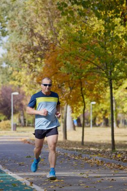 Bir sonbahar günü parkta koşan orta yaşlı bir adamın portresi..