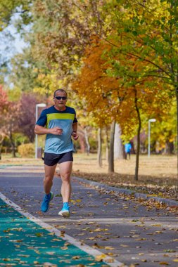 Bir sonbahar günü parkta koşan orta yaşlı bir adamın portresi..