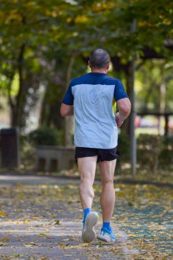 Bir sonbahar günü parkta koşan orta yaşlı bir adamın portresi..
