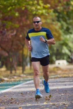 Bir sonbahar günü parkta koşan orta yaşlı bir adamın portresi..