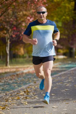 Bir sonbahar günü parkta koşan orta yaşlı bir adamın portresi..