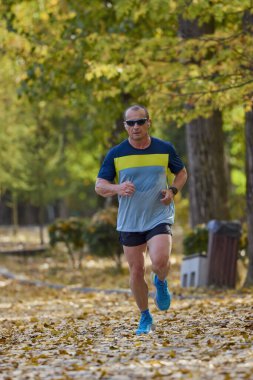 Bir sonbahar günü parkta koşan orta yaşlı bir adamın portresi..