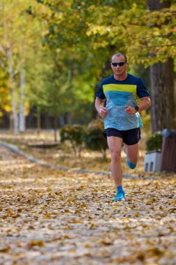 Bir sonbahar günü parkta koşan orta yaşlı bir adamın portresi..
