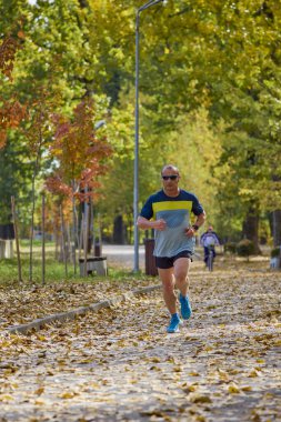 Bir sonbahar günü parkta koşan orta yaşlı bir adamın portresi..