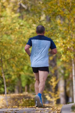 Bir sonbahar günü parkta koşan orta yaşlı bir adamın portresi..