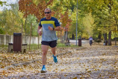 Bir sonbahar günü parkta koşan orta yaşlı bir adamın portresi..