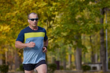 Bir sonbahar günü parkta koşan orta yaşlı bir adamın portresi..