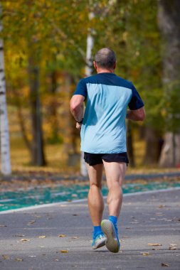 Bir sonbahar günü parkta koşan orta yaşlı bir adamın portresi..