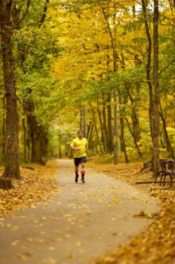 Bir sonbahar günü parkta koşan orta yaşlı bir adamın portresi..