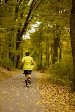 Bir sonbahar günü parkta koşan orta yaşlı bir adamın portresi..