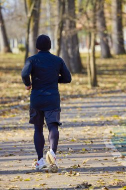 Bir sonbahar günü parkta koşan orta yaşlı bir adamın portresi..