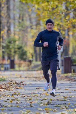 Bir sonbahar günü parkta koşan orta yaşlı bir adamın portresi..