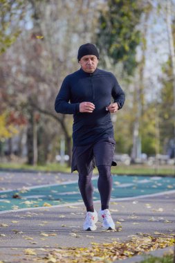 Bir sonbahar günü parkta koşan orta yaşlı bir adamın portresi..