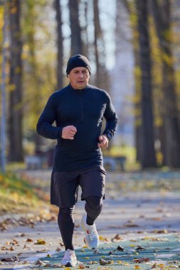 Bir sonbahar günü parkta koşan orta yaşlı bir adamın portresi..