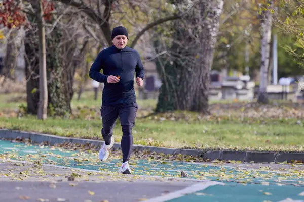 Bir sonbahar günü parkta koşan orta yaşlı bir adamın portresi..