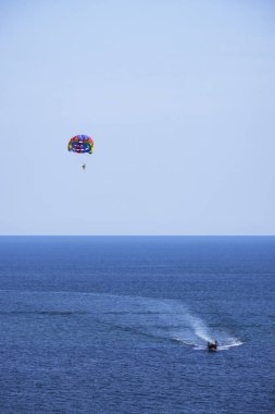 Tatil köyünde deniz kenarında paraşütle atlayan turistlerin görüntüsü. Turizm kavramı.