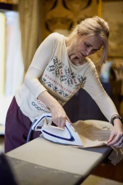 Ütü masasıyla ütü yapan bir kadının portresi. Bulanık arkaplan.