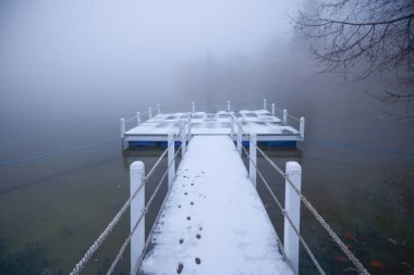 Sisin içinde kaybolan bir gölün üzerinde duba olan kış manzarası..