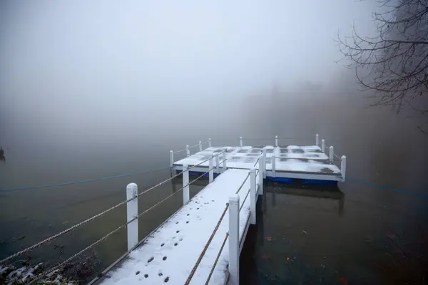 Winter landscape with a pontoon on a lake that gets lost in the fog.