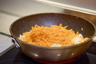 Soğanlı bir tava, fırında biber ve havuç pişiyor.