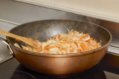 Soğanlı bir tava, fırında biber ve havuç pişiyor.