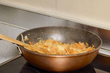 Soğanlı bir tava, fırında biber ve havuç pişiyor.