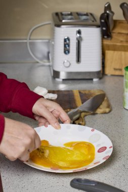 Bir kadının elleri çatalla yumurtayı tabakta karıştırıp hazırlıyor..