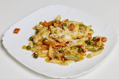 Sebzeli makarna ve masada parmesan peyniri.