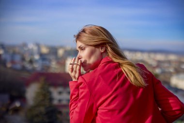 Güneşli bir günde balkonda sigara içen bir kadın..