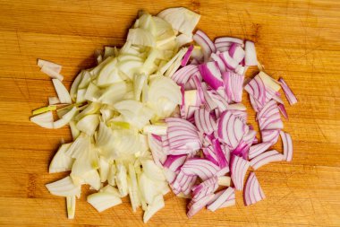 Tahtada doğranmış kırmızı ve sarı soğanlar.