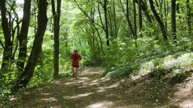 4K, güçlü orta yaşlı bir adam ormanda ağır çekimde koşuyor..