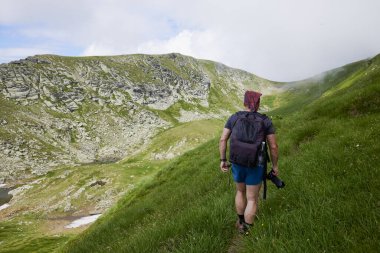 Orta yaşlı bir adam dağda yürüyor.
