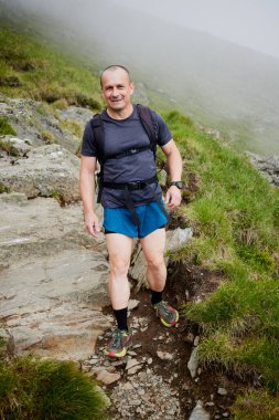Orta yaşlı bir adam dağda yürüyor.
