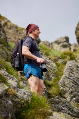 Orta yaşlı bir adam dağda yürüyor.