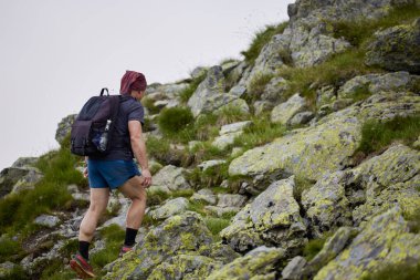 Orta yaşlı bir adam dağda yürüyor.