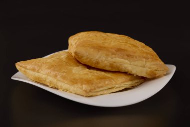 (Siyah arka planda beyaz tabakta peynirli turta..