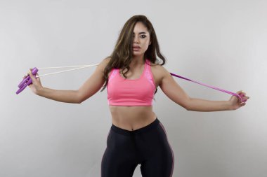 Farklı pozlarda iple gezen güzel bir kadın gri arka planda yalnız poz verir.