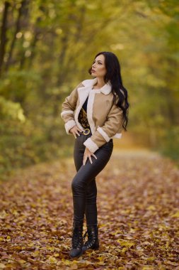Güz ormanlarında bir yolda ceketi ve pantolonu dolu güzel bir kadının portresi..