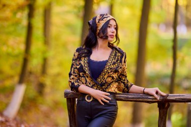 Başörtülü güzel bir kadın sonbahar arkaplanlı poz veriyor.