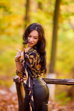 Elinde eşarpla güzel bir kadın sonbahar manzarasının tadını çıkarıyor.