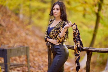 Elinde eşarpla güzel bir kadın sonbahar manzarasının tadını çıkarıyor.