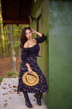 Sonbaharda kulübenin yanında şapkası olan güzel bir kadın.